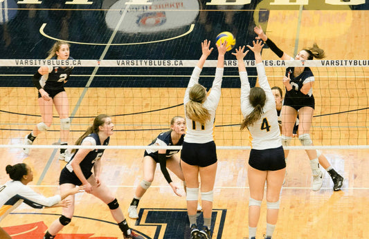 Women in black and white uniforms playing volleyball