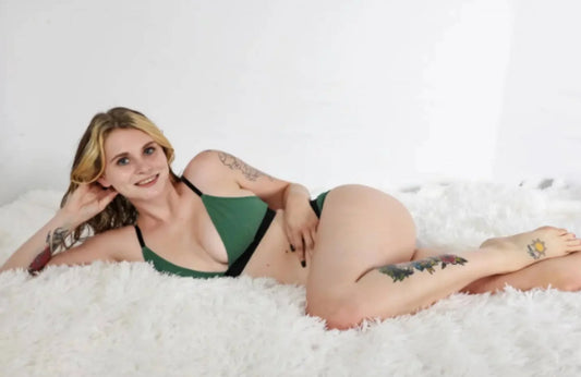  blonde woman wearing a green triangle bralette and panties lies on one side propped on her right elbow