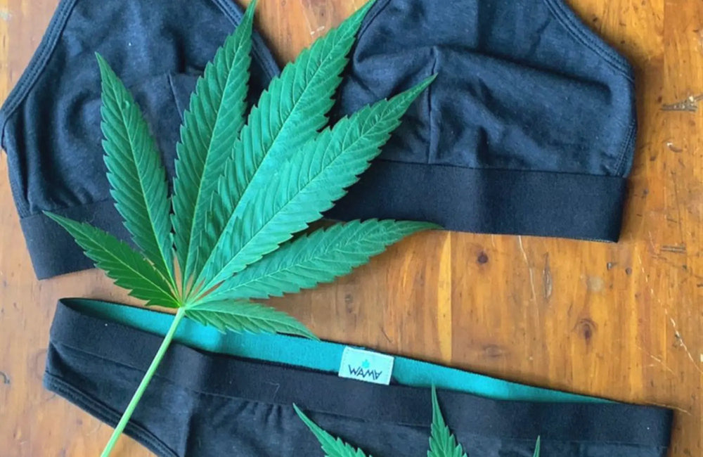 A pair of black underwear and hemp leaves laying on a wooden surface.