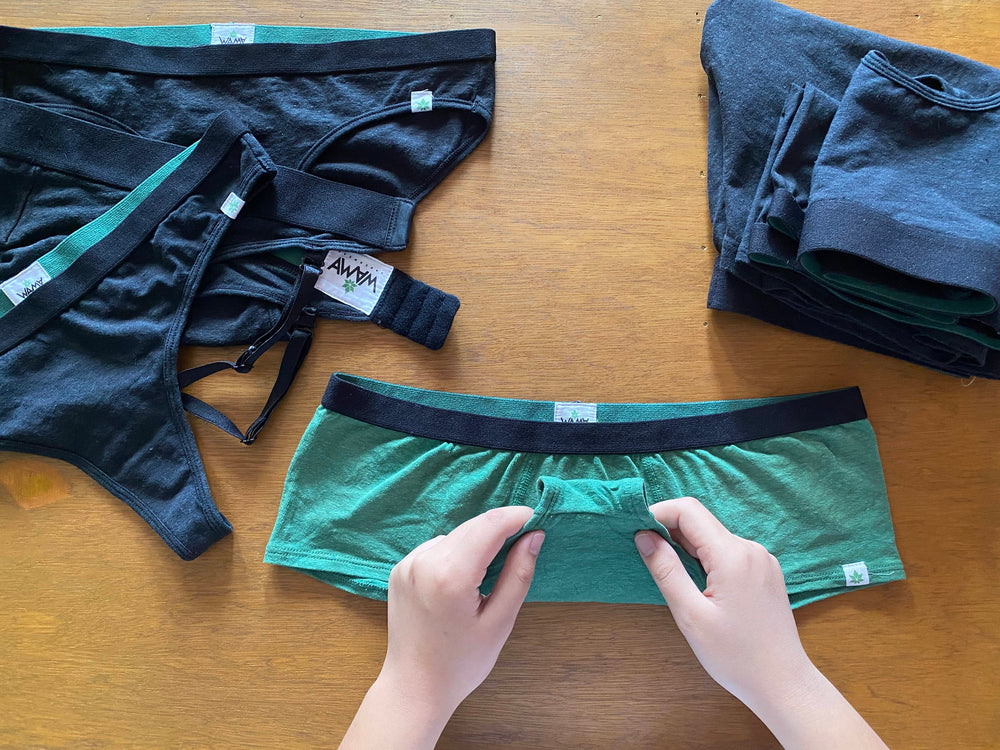 A person folding a pair of green WAMA boy shorts underwear to learn how to organize underwear.