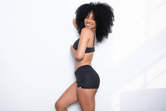 A woman standing and smiling wearing WAMA boy shorts underwear, one of the best boxers for women.