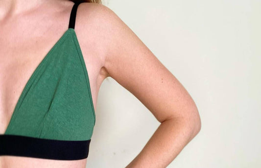 the right side of a woman wearing a triangle bralette, in green with her hand on her hip