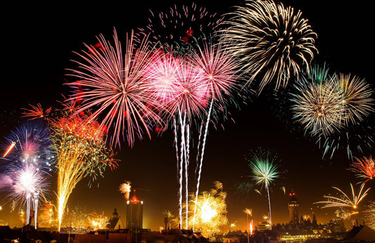 colorful fireworks light up the sky above a city skyline