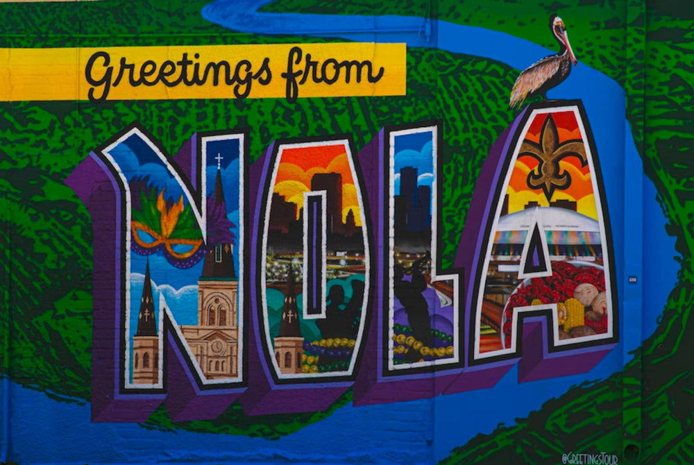 colorfully painted mural that reads “greetings from NOLA” with some of the most iconic sights painted in the letters 
