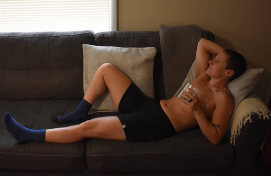 person lounging on a sofa with one arm behind their head in black boxer briefs 