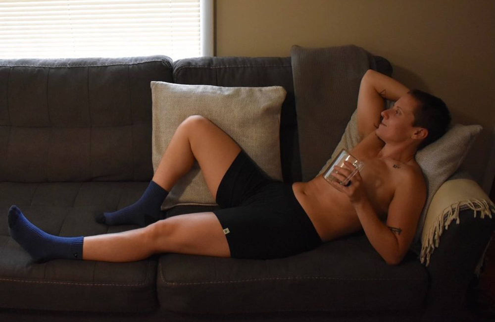 person lounging on a sofa with one arm behind their head in black boxer briefs 