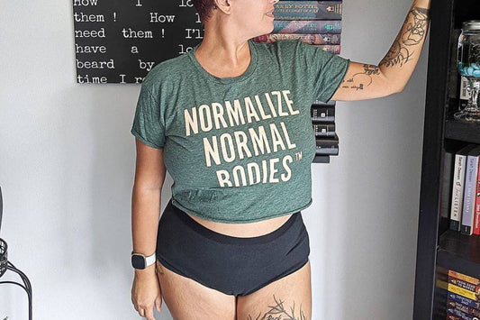 A woman wears a Normalize Normal Bodies shirt and WAMA Underwear.