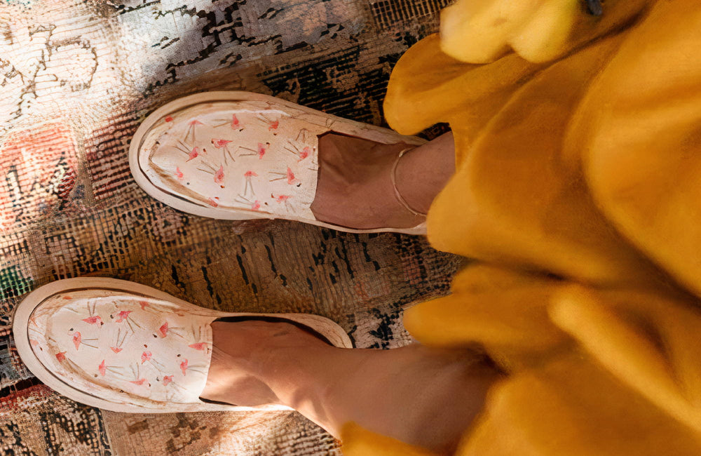 Feet in floraal shoes from above, standing on a colorful carpet