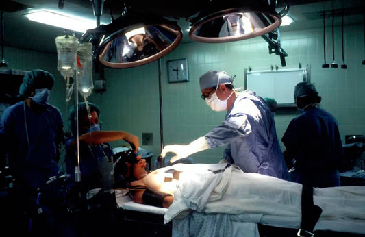 three doctors operate on a sedated person lying on an operating table