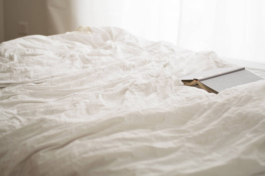 Crisp white hemp sheets with an open book laid on top.