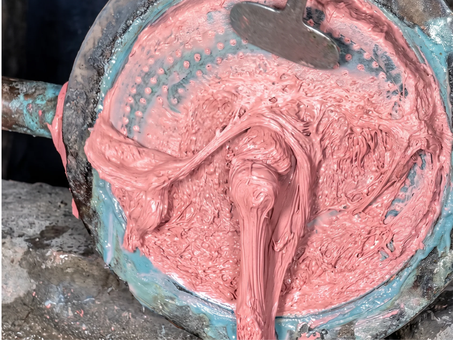 Molten pink plastic churning inside an industrial extruder, the raw material polyester is spun from