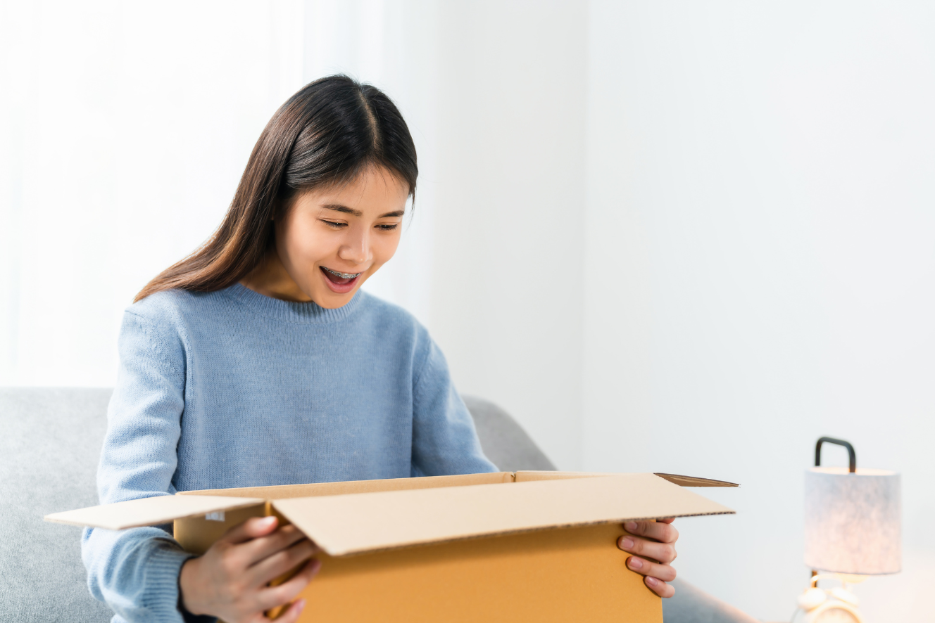 A surprised girl excitedly opening a box.