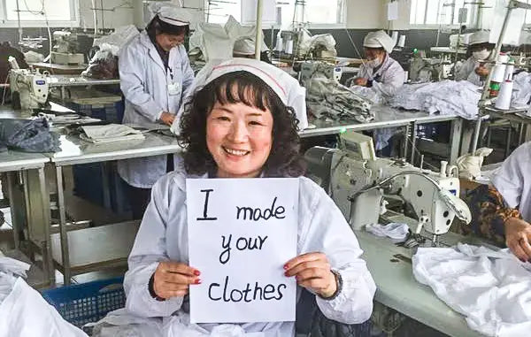 Garment factory worker holding an I made your clothes sign